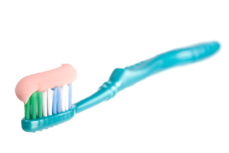 A single toothbrush with toothpaste on white