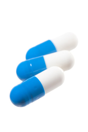 Blue pills isolated on white. Focus on the front capsule.