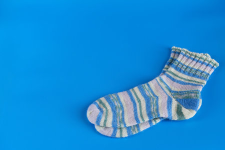 Hand knitted warm winter socks on blue background. view from the topの写真素材
