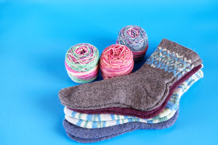 Hand knitted warm winter socks and threads on blue background. view from the topの写真素材