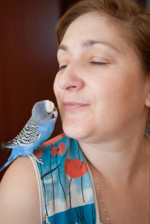 A woman with a budgie on her shoulder