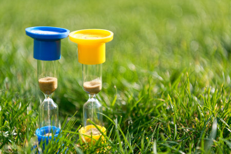 Hourglasses on the green grass natural background