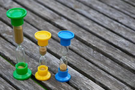 Three hourglasses on rustic weathered wooden table. Time is runningの写真素材