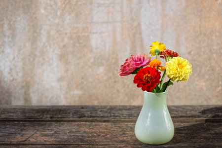 Bouquet of flowers in a glass vase on an old wooden table against a funky plaster backgroundの写真素材