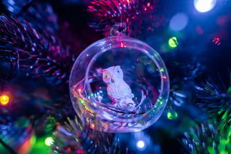 Christmas tree decoration owl in a glass ball in the light of garlands.の写真素材