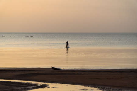 A man with an oar swims standing on a board on the Gulf of Finland.の写真素材