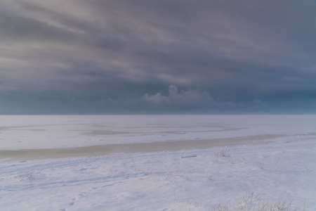 Russia. View from the southern coast of Kronstadt to the frozen Gulf of Finland and dark clouds on the horizon.の写真素材