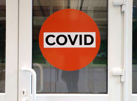 Caution, COVID. A red sign on the door with the inscription COVID.