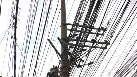 Silhouetted tangled lines appear under cloudy weather, lines contrasting sky, lines showing urban...