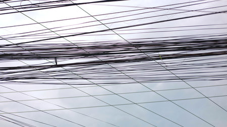 Chaotic urban power lines stretch across cloudy sky, power lines creating messy network, power lines...
