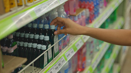 Young woman grabs cleaning spray grocery shelf, young woman picks disinfectant bottle pharmacy aisle, hand selects hygiene product, home routine moment, ideal lifestyle videosの写真素材
