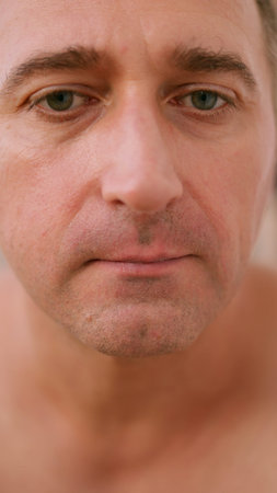 Vertical photo Man grooming morning, Man carefully shaving in sunlight, Focused individual engaging in personal grooming beneath warm morning light, Man concentrating on shavingの写真素材