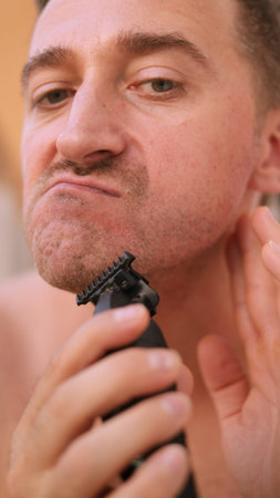 Vertical photo Individual carefully shaping his facial hair with precision and focus, Person...