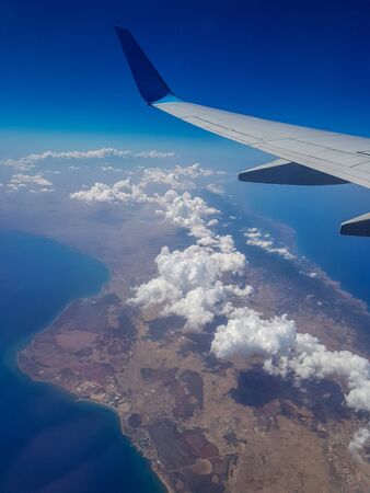 View of the Mediterranean island from the porthole of an airplane, among the clouds. In flightの写真素材