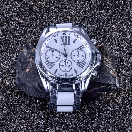 An old mechanical watch lying on a stone, having seen a lot in its timeの写真素材