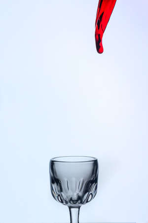 A splash of red wine in a glass on a white background.の写真素材