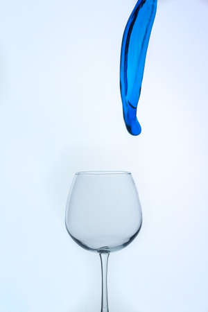 A splash of blue liquid in a glass on a white background.の写真素材