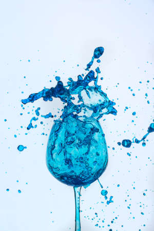 A splash of blue liquid in a glass on a white background.の写真素材