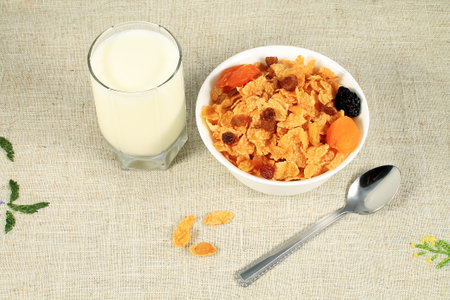 Cornflakes with raisins and glass of milk on table