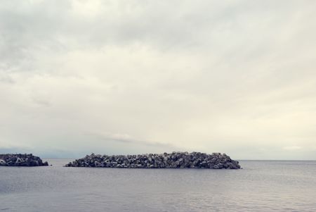 pale cloudy seascape with breakwater structure