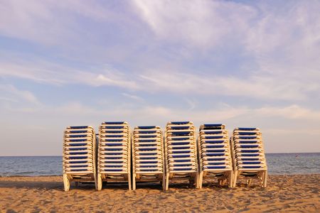 row of beach seats on the sand waiting for the night with evening sky backgroundの写真素材