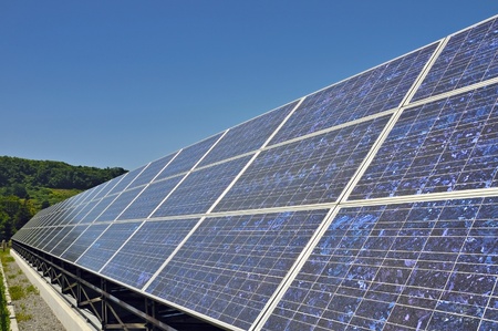 bright highly detailed solar panels stand under clear blue skyの写真素材