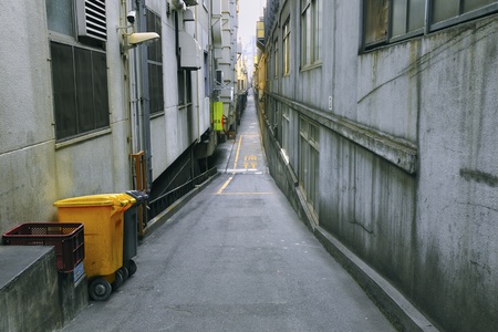 very long and straight backyard pathway with yellow waste urn in Tokyo cityの写真素材