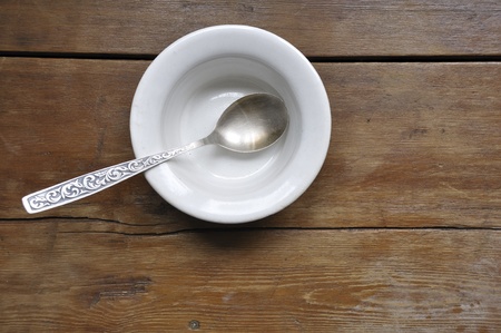 empty soup bowl with vintage silver spoon on  the wooden kitchen table backgroundの写真素材