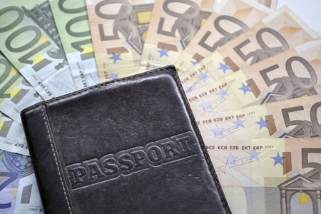 enveloped passport lay over Euro banknotes; selective focus on Passport word 