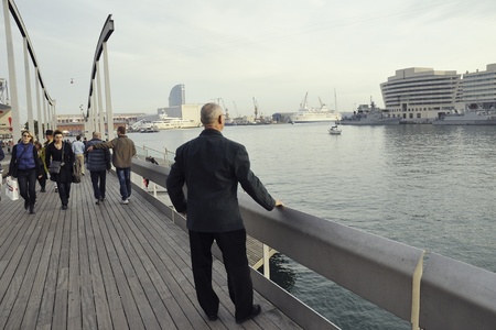 Barcelona, Spain - November 13, 2009 : Man look at scenic view over metallic handrails of pedestrian wooden pathwayat  Rambla del Mar street in Barcelona Port area.のeditorial素材