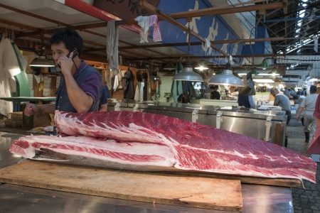 Tokyo, Japan - September 27, 2008: salesman talks by phone behind the big raw tuna body laying on the table top on the world famous Tokyo Tsukiji fish market.のeditorial素材