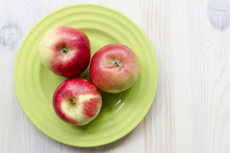 three red apple on the green plateの写真素材