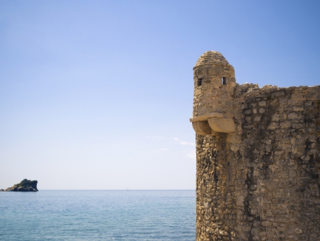 fragment of ancient Mediterranean fort with sunny seascape behindの写真素材