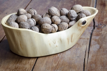 scenic wooden bowl full of walnuts on the vintage wooden table with focus on nutsの写真素材