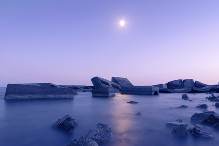 night landscape with sea pier ruins and bright moon at the skyの写真素材