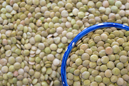many green lentil beans background with focus on small blue cup fragmentの写真素材