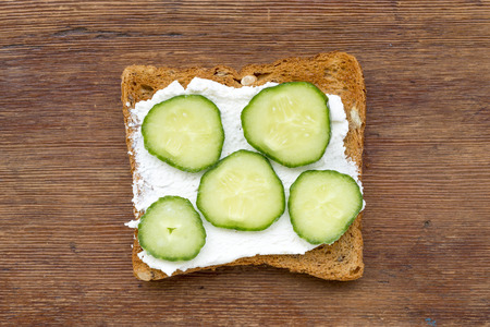 fried toast with soft cheese and cucumber slices on vintage woodの写真素材