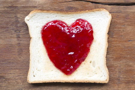 fried toast with red jam in shape oh heart on vintage woodの写真素材
