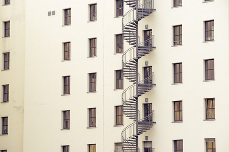 spiral metallic fire escape ladder at the backyard of modern building wallの写真素材