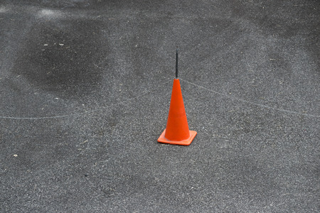 red prohibition cone with metallic chain fence set on the road asphaltの写真素材