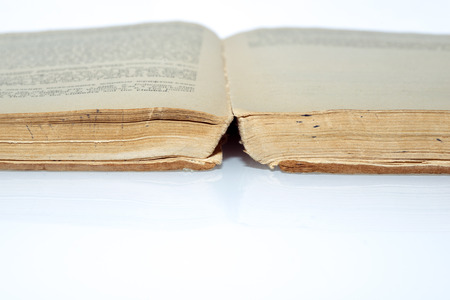 yellowish ancient book open on the white reflective surfaceの写真素材