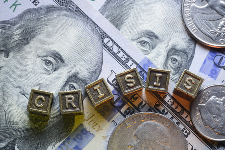 crisis word made from metallic letter blocks over dollar banknotes