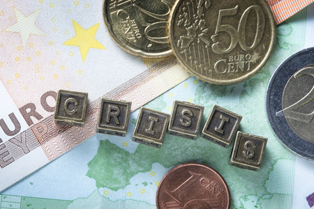 crisis word made from metallic letter blocks over euro banknotes and coinsの写真素材