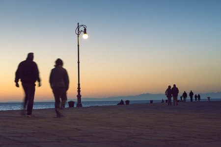 many people walk along the pier by evening in Triest, Italyの写真素材