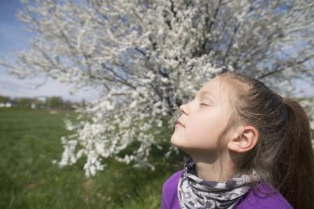 child girl enjoying spring sun outdoor with closed eyesの写真素材