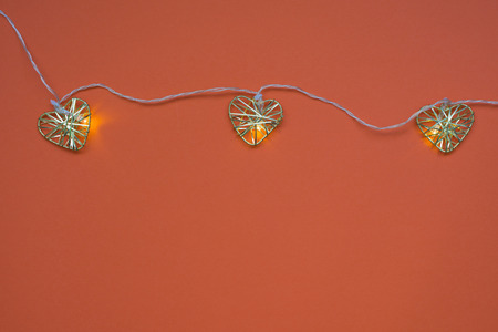 three hearts garland on red background with blank space
