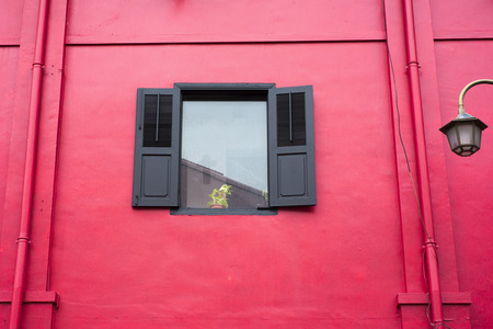 bright red wall with single window and home plant on windowsillの写真素材
