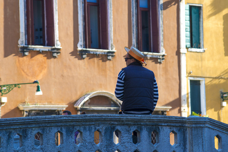 VENICE - OCTOBER 17: gondolier in traditional dress relaxing on bridge by evening in Venice, Italy on October 17, 2015. Gondolier is one of the oldest professions in the world controlled by a Guild.のeditorial素材