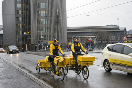 BERLIN, GERMANY- JANUARY 15: two delivery workers in yellow uniform ride bicycles by rainy street in Berlin, Germany on January 15, 2015のeditorial素材