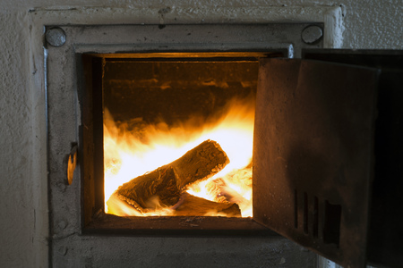 fire inside open furnace with focus on burning logの写真素材